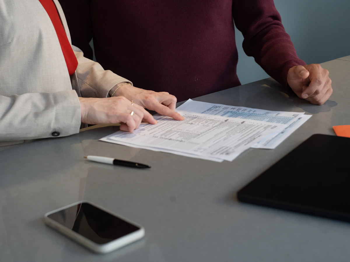 Deux personnes examinent ensemble des documents posés sur une table de réunion.